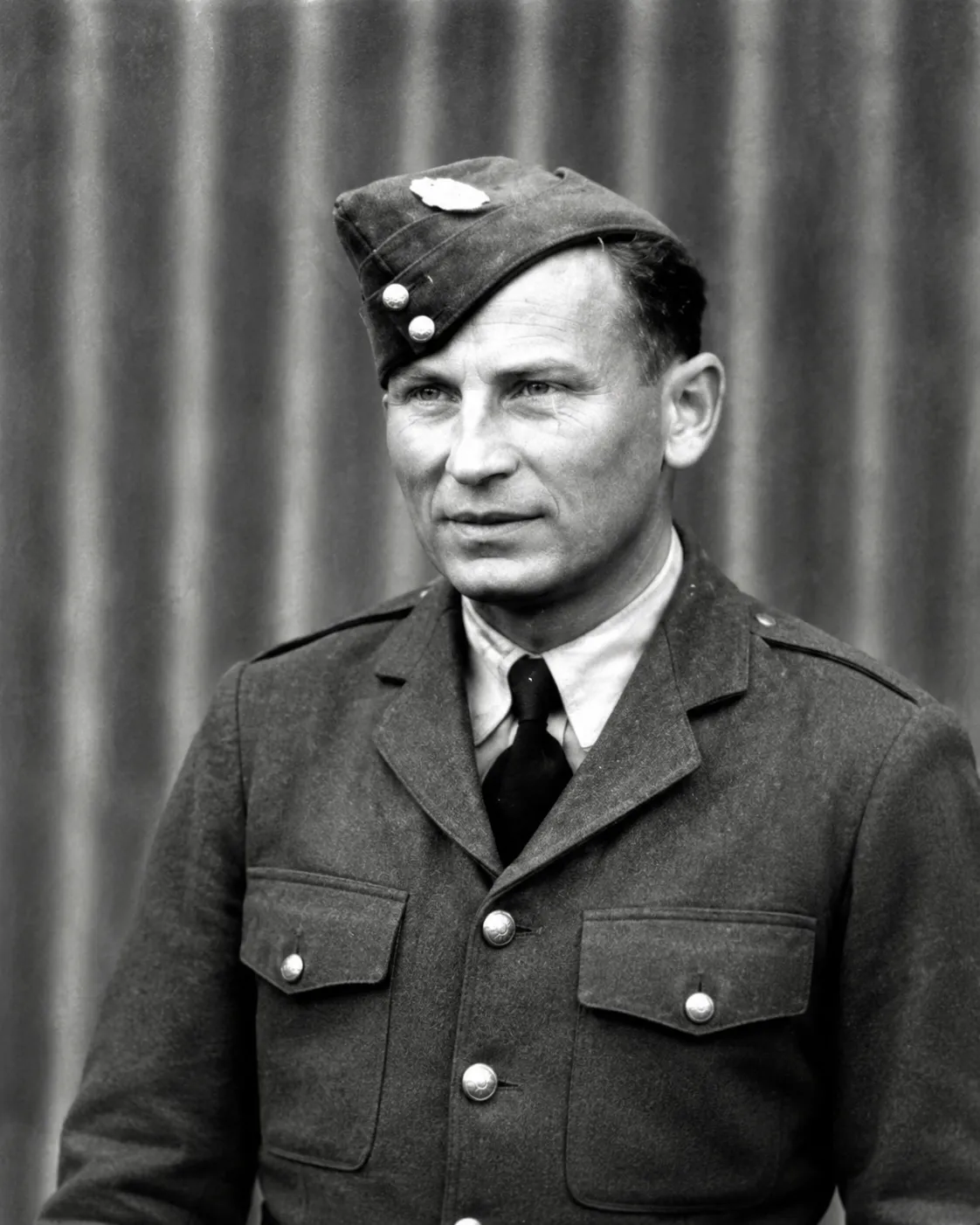Studio portrait of Witold Czernichowicz in Polish Air Force uniform, wearing a forage cap with eagle badge.